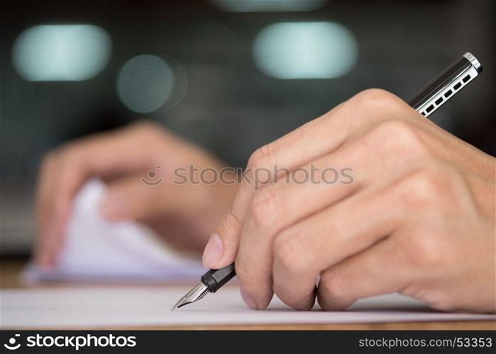 Businessman writing in a document. Focus on the tip of the pen.