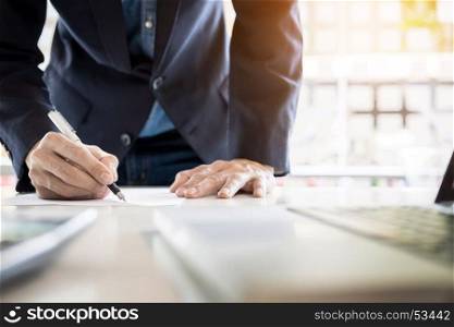 Businessman writing in a document. Focus on the tip of the pen.