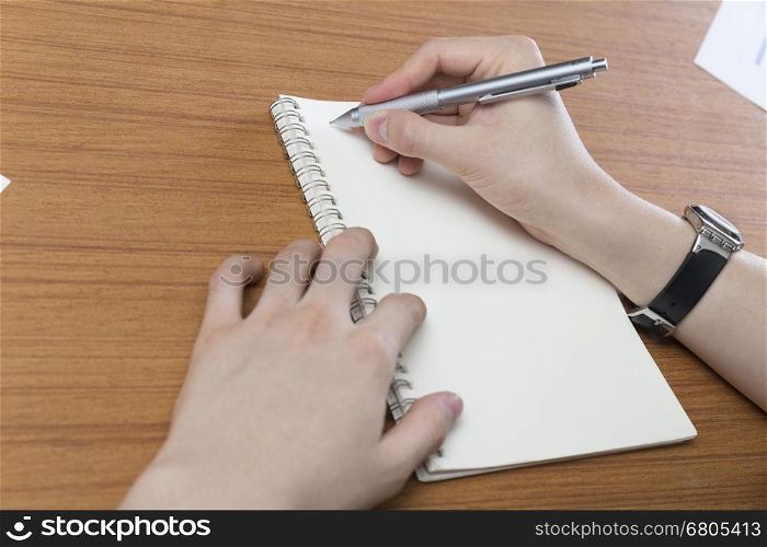 businessman writing note on notepad on office desk