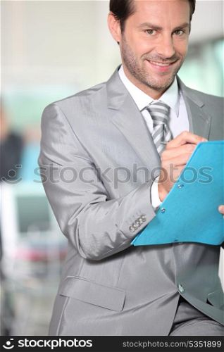 Businessman writing notes in a blue folder