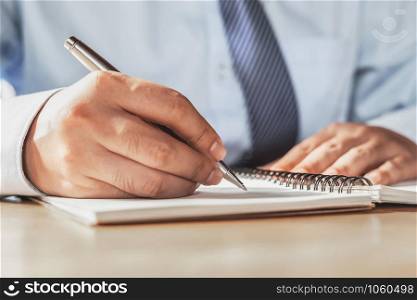 businessman writing on note book in office