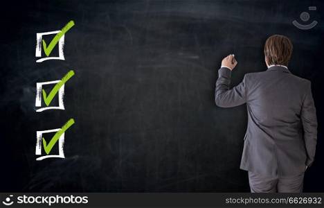 Businessman writing with checkbox concept on blackboard.. Businessman writing with checkbox concept on blackboard