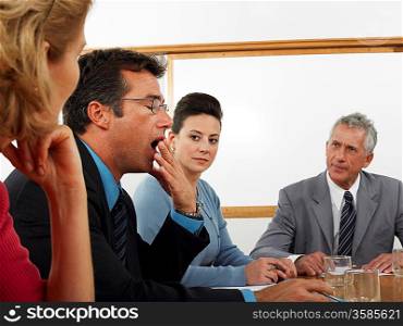 Businessman yawning in conference meeting
