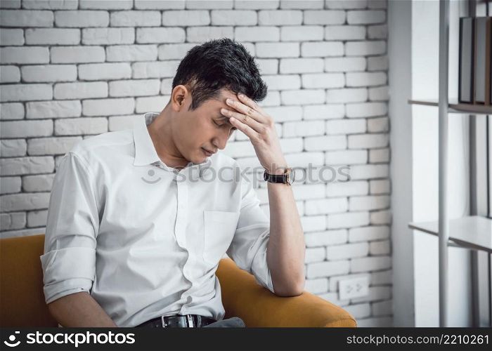 Businessman young asian having a migraine or headache, struggle with dizziness on sitting couch at home
