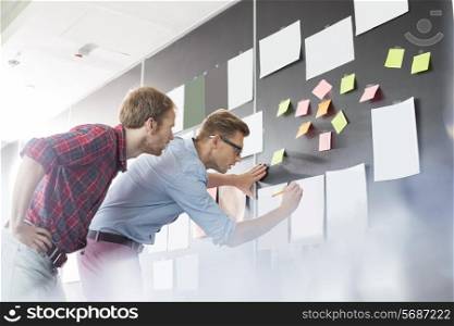Businessmen analyzing documents on wall in office
