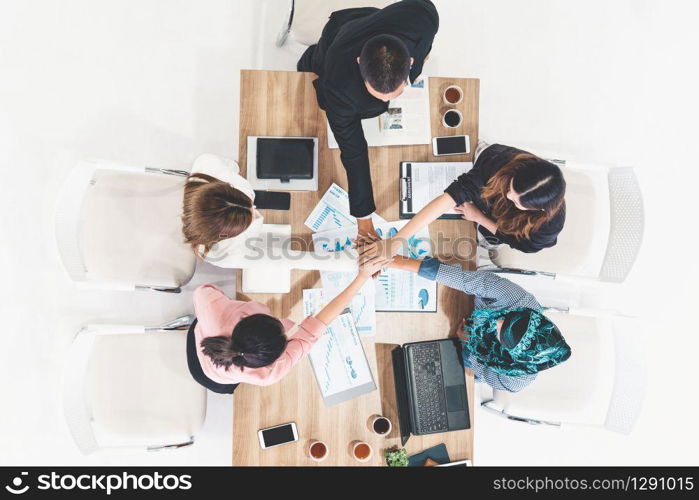 Businessmen and businesswomen joining hands in group meeting at multicultural office room showing teamwork, support and unity in business. Diversity workplace and corporate people working concept.