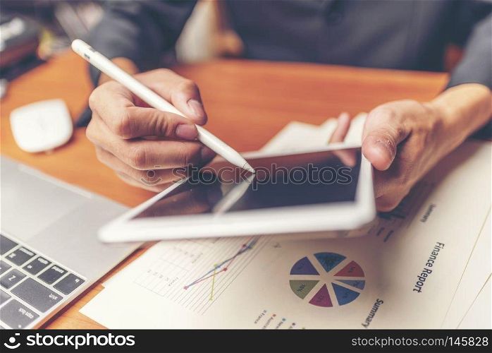 Businessmen are analyzed data from report using smartphone and laptop computer.