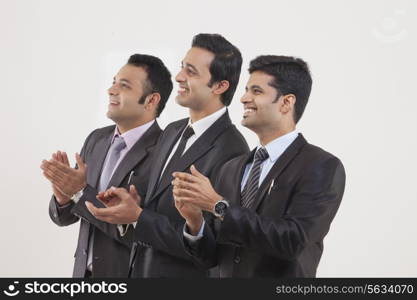 Businessmen clapping while watching cricket match