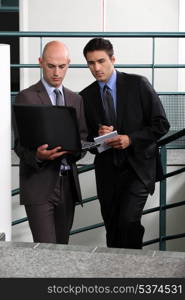 Businessmen comparing notes in stairwell