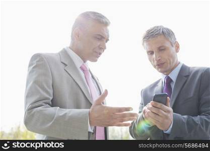 Businessmen discussing over mobile phone outdoors