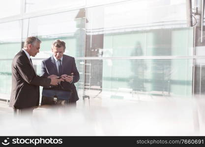 Businessmen discussing plans over smartphone in the airport