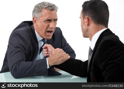 Businessmen fighting at desk