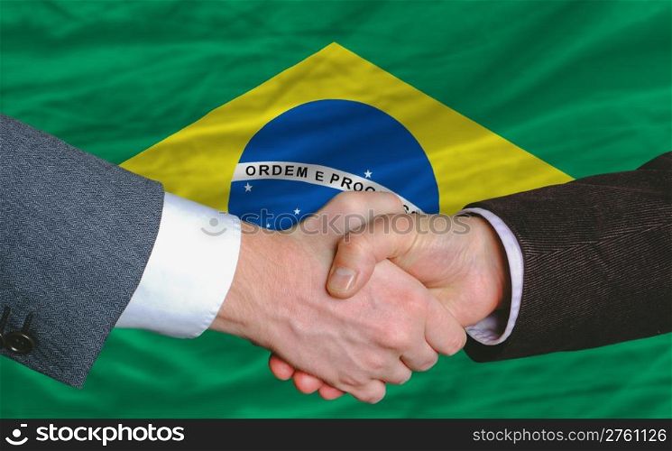 businessmen handshake after good deal in front of brazil flag