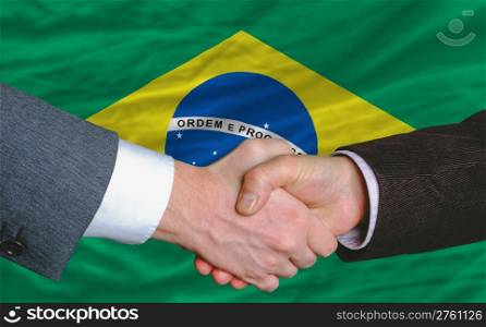businessmen handshake after good deal in front of brazil flag