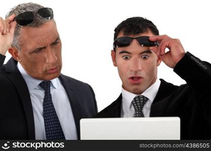 Businessmen looking at their laptops