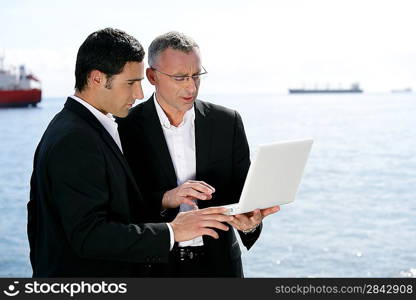 Businessmen outdoors working on laptop