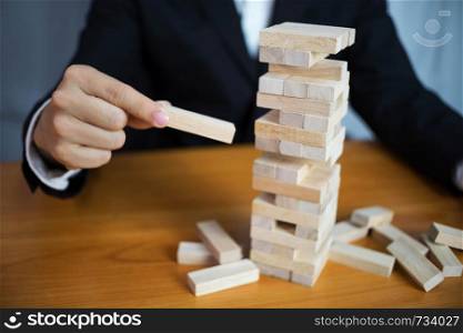 Businessmen picking wood blocks to fill the missing dominoes. Growing business concept.