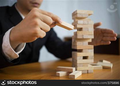 Businessmen picking wood blocks to fill the missing dominos and protect domino to fail. Growing business concept.