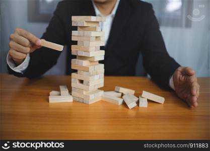 Businessmen picking wood blocks to fill the missing dominos and protect domino to fail. Growing business concept.