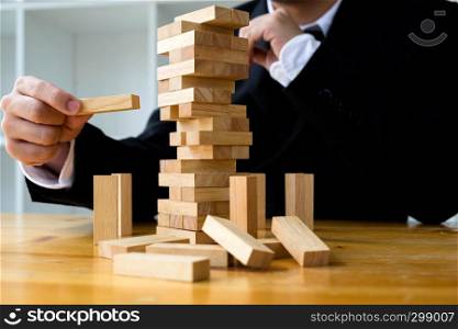 Businessmen picking wood blocks to fill the missing dominos. Growing business concept.