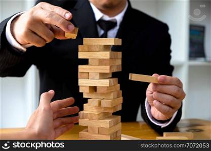 Businessmen picking wood blocks to fill the missing wood blocks and protect wood blocks to fail. Growing business concept.