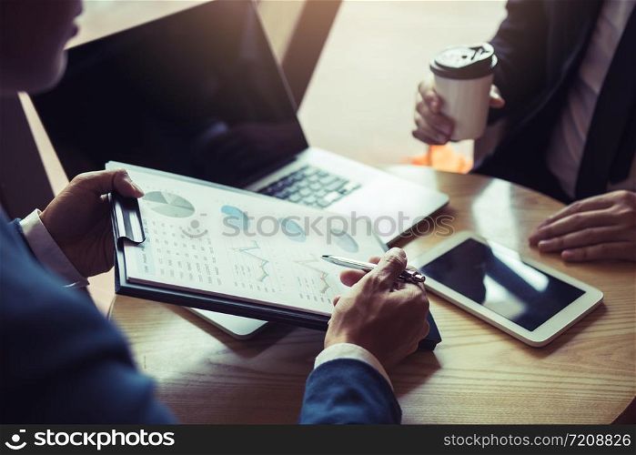 Businessmen pointed out the company performance chart on the table during a strategy discussion and drank coffee in the morning in the office.