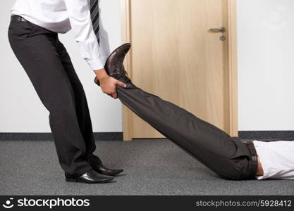 Businessmen pulling colleague&rsquo;s leg at office