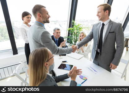 Businessmen shaking hands. Businessmen shaking hands at meeting in office, business team clapping