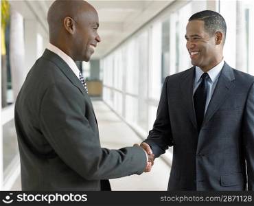 Businessmen shaking hands in hallway