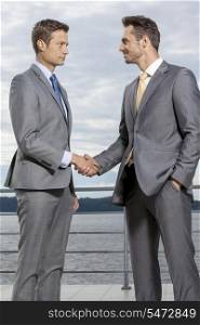 Businessmen shaking hands on terrace against sky