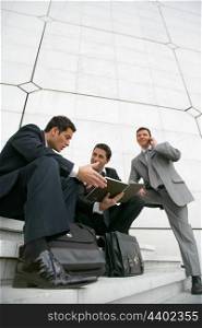 Businessmen sitting outside a city building
