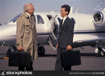 Businessmen Talking On Runway With Jet In Background
