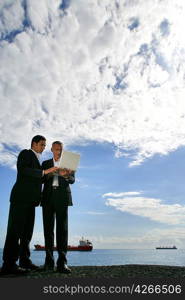 Businessmen using a laptop against a blue sky with fluffy clouds