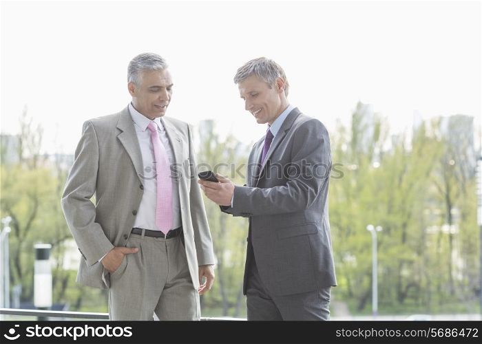 Businessmen using cell phone together outdoors