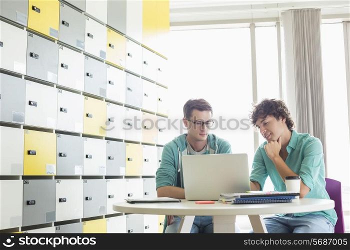 Businessmen using laptop at table in locker room at creative office