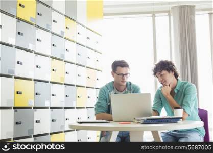 Businessmen using laptop at table in locker room at creative office