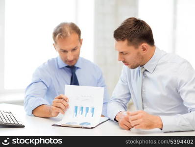 businessmen with notebook discussing graphs on meeting