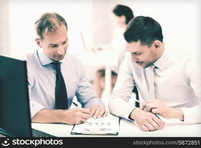 businessmen with notebook discussing graphs on meeting