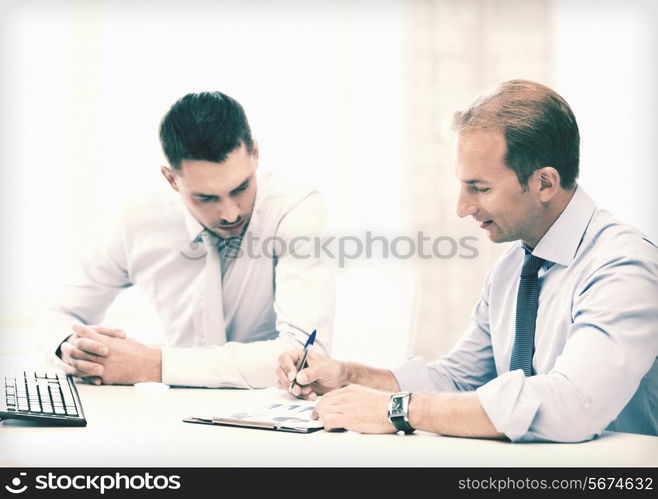 businessmen with notebook discussing graphs on meeting