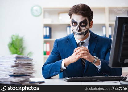 Businessmsn with scary face mask working in office. Businessman with scary face mask working in office