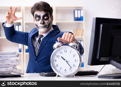 Businessmsn with scary face mask working in office. Businessman with scary face mask working in office