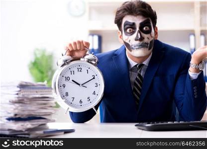 Businessmsn with scary face mask working in office. Businessman with scary face mask working in office