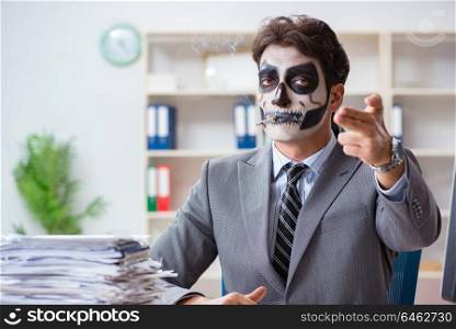 Businessmsn with scary face mask working in office. Businessman with scary face mask working in office