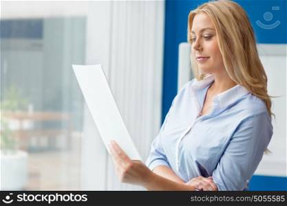 Businessowman standing next to window with papers