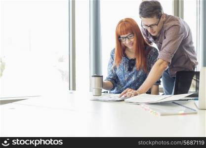 Businesspeople analyzing file together at desk in creative office