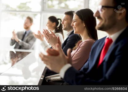 Businesspeople applauding while in a meeting at modern office