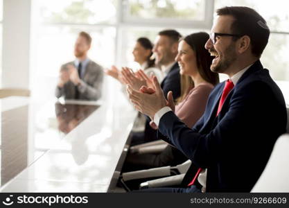 Businesspeople applauding while in a meeting at modern office