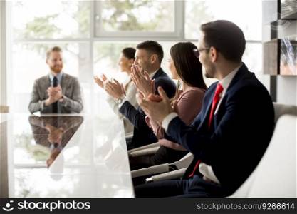 Businesspeople applauding while in a meeting at modern office