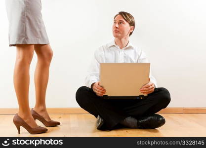 Businesspeople at home; he is sitting with laptop on the floor