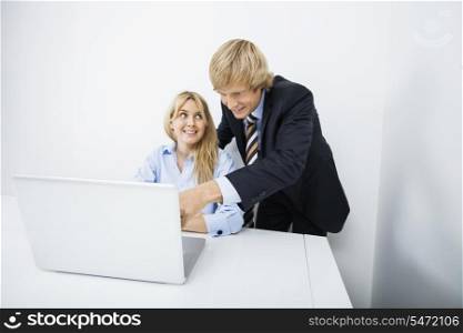 Businesspeople discussing over laptop in office